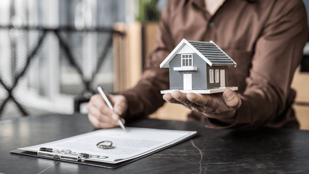Homme tenant une maquette de maison et signant un contrat